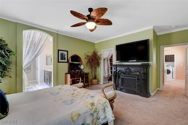 bedroom featuring washer / dryer, ceiling fan, light colored carpet, ensuite bathroom, and crown molding