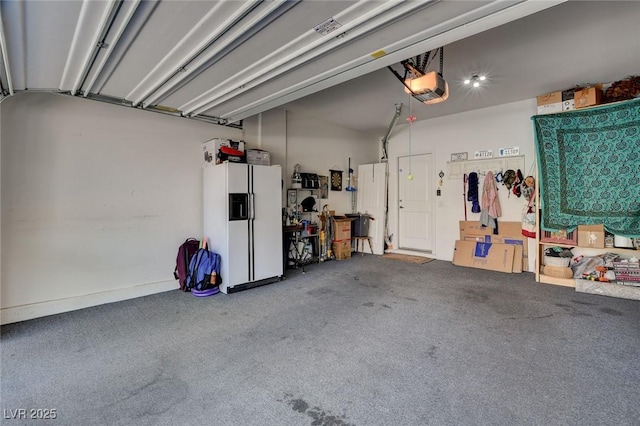 garage with a garage door opener and white fridge with ice dispenser