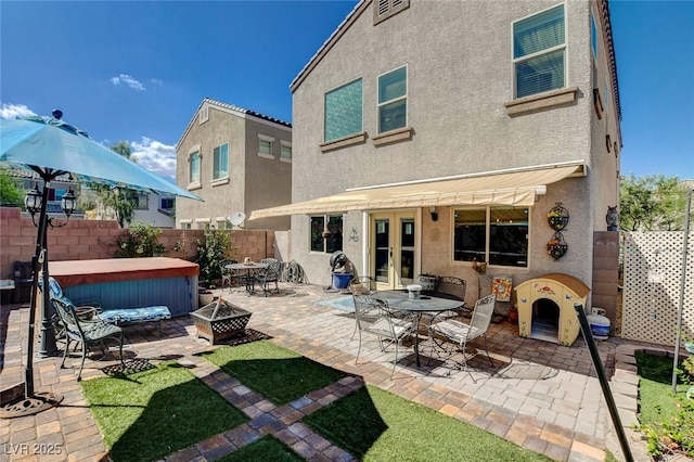 back of property featuring an outdoor fire pit, a hot tub, and a patio