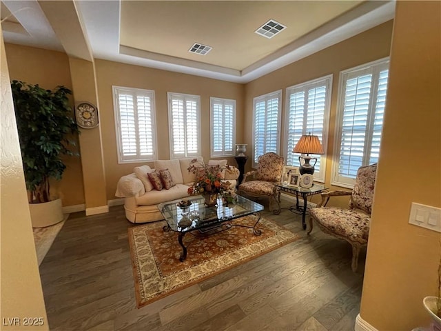 living room with hardwood / wood-style floors and a tray ceiling