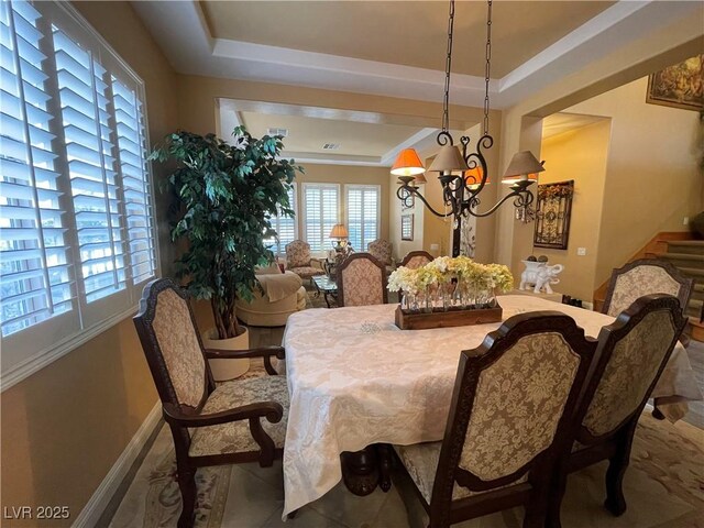 dining area featuring an inviting chandelier and a tray ceiling