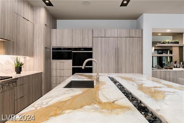 kitchen featuring light stone countertops, sink, light brown cabinets, and double oven