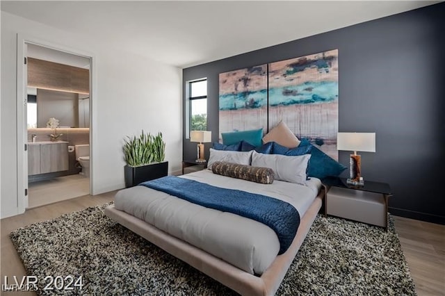 bedroom with ensuite bathroom and light wood-type flooring