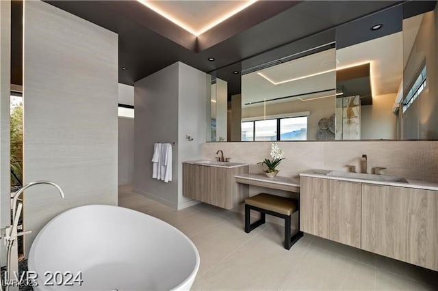 bathroom with a tub, tile patterned floors, vanity, and a tray ceiling