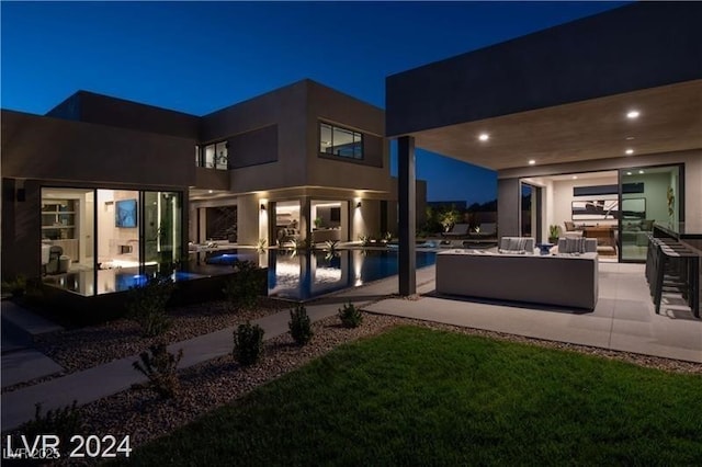 back house at twilight with a patio area, an outdoor hangout area, and a swimming pool