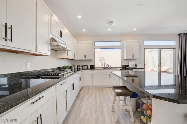 kitchen featuring white cabinetry, dark stone counters, light hardwood / wood-style floors, sink, and stainless steel gas cooktop