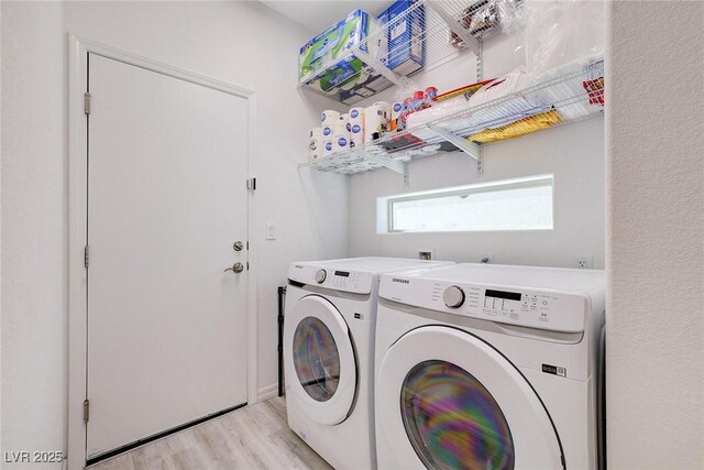 laundry room with separate washer and dryer and light hardwood / wood-style flooring