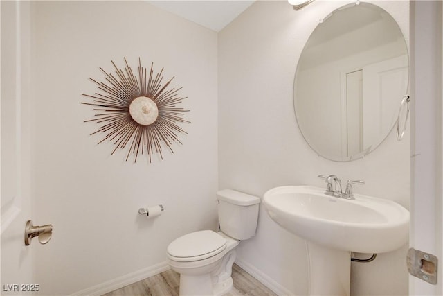 bathroom with baseboards, toilet, and wood finished floors