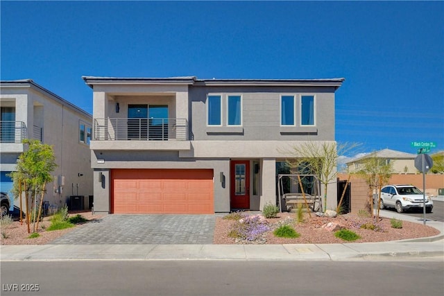 contemporary house featuring driveway, a balcony, a garage, stucco siding, and central AC unit