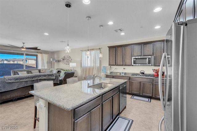 kitchen featuring pendant lighting, appliances with stainless steel finishes, sink, a kitchen breakfast bar, and a center island with sink