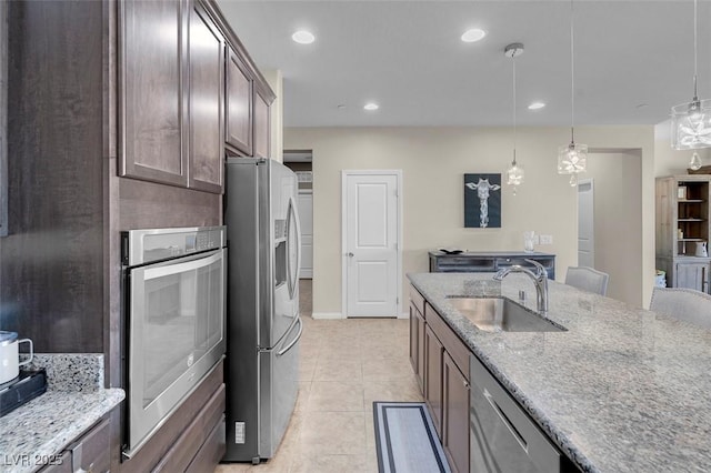 kitchen featuring sink, pendant lighting, dark brown cabinetry, and appliances with stainless steel finishes