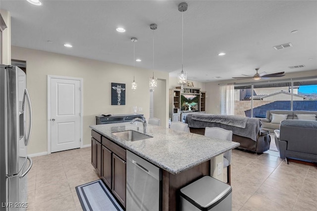 kitchen with light stone countertops, sink, pendant lighting, an island with sink, and stainless steel appliances