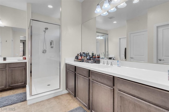 bathroom with a shower with door, vanity, and tile patterned flooring