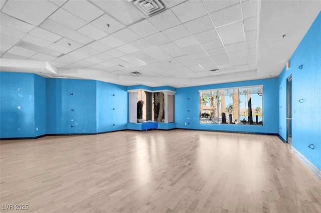 exercise room with light hardwood / wood-style floors and a paneled ceiling