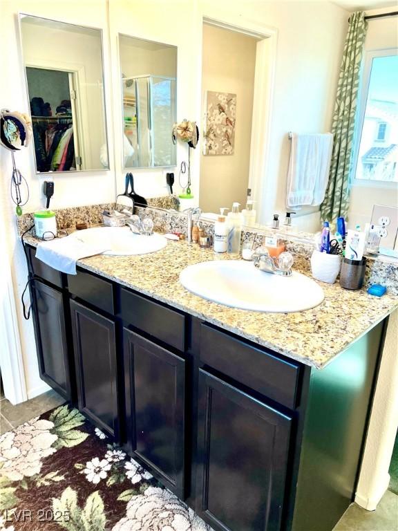 bathroom featuring vanity, a shower with shower door, and tile patterned flooring