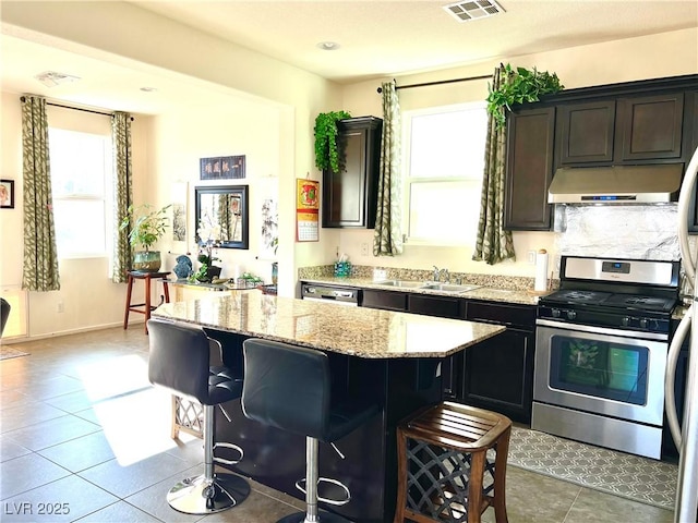 kitchen featuring sink, dark brown cabinets, a kitchen breakfast bar, and appliances with stainless steel finishes