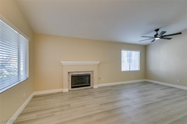 unfurnished living room featuring light hardwood / wood-style floors, ceiling fan, and a tiled fireplace