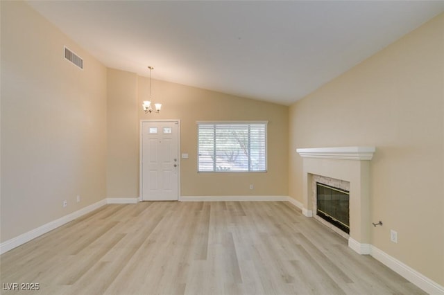 unfurnished living room featuring light wood-type flooring, vaulted ceiling, and a notable chandelier