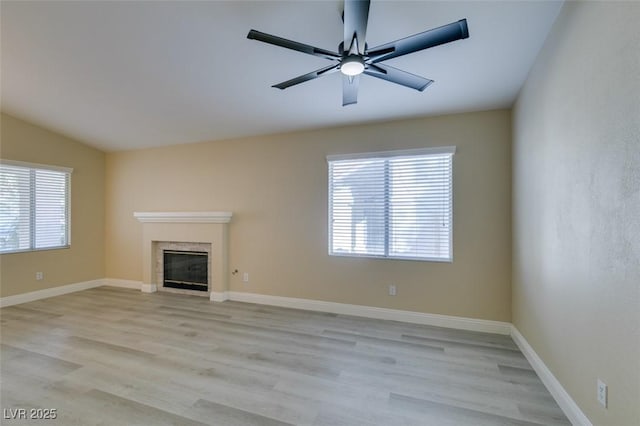 unfurnished living room featuring light hardwood / wood-style floors, lofted ceiling, ceiling fan, and a fireplace