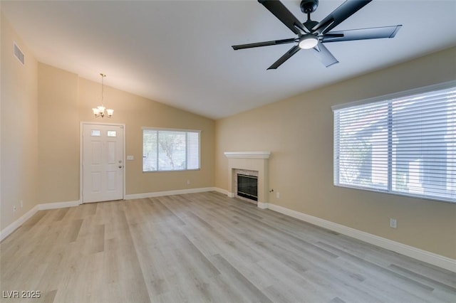 unfurnished living room with vaulted ceiling, a healthy amount of sunlight, light hardwood / wood-style flooring, and a fireplace