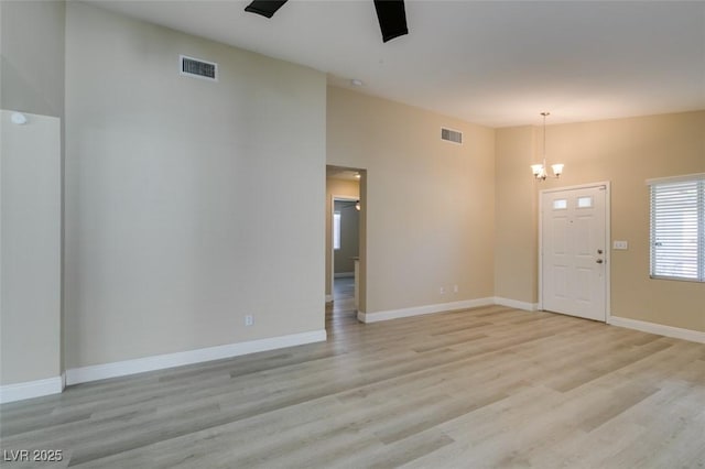 entrance foyer with light wood-type flooring, ceiling fan with notable chandelier, and lofted ceiling