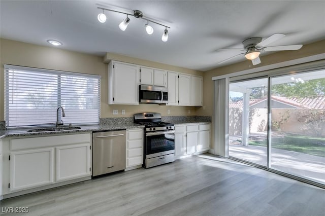 kitchen featuring light hardwood / wood-style flooring, appliances with stainless steel finishes, sink, white cabinets, and light stone counters