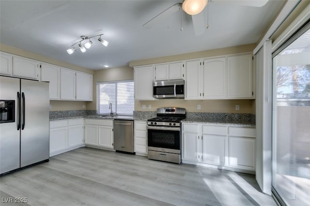 kitchen featuring white cabinetry, light stone counters, light hardwood / wood-style flooring, and appliances with stainless steel finishes