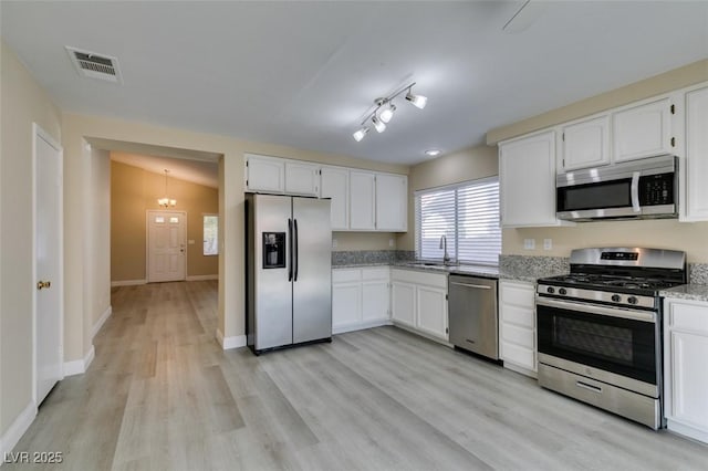 kitchen with sink, white cabinets, light stone countertops, and appliances with stainless steel finishes