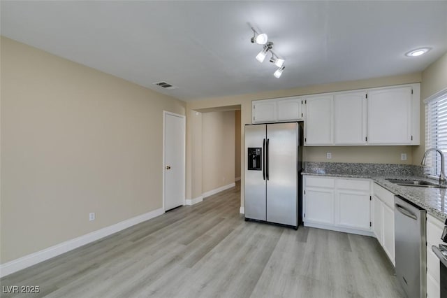 kitchen featuring sink, light stone counters, white cabinetry, and appliances with stainless steel finishes