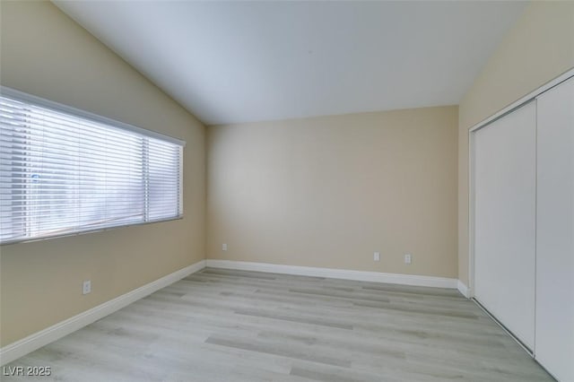 unfurnished bedroom with light wood-type flooring, a closet, and lofted ceiling