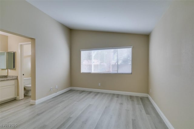 spare room with light hardwood / wood-style flooring and lofted ceiling