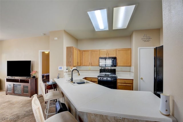 kitchen with kitchen peninsula, light brown cabinets, sink, light colored carpet, and black appliances