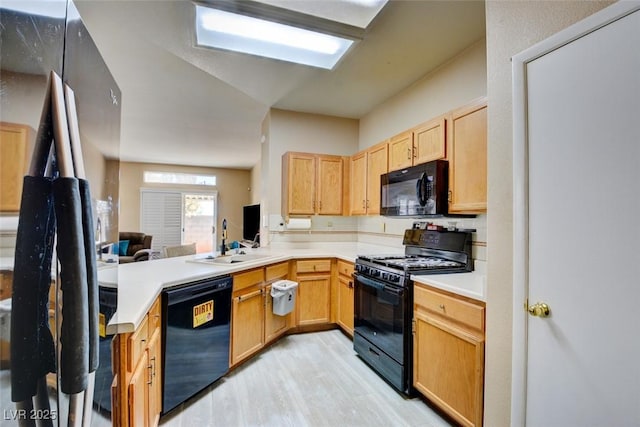 kitchen with black appliances, light brown cabinets, sink, kitchen peninsula, and light hardwood / wood-style flooring