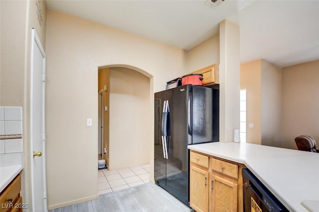 kitchen with light brown cabinetry, light tile patterned floors, and black appliances