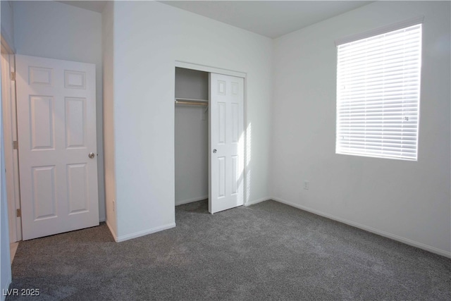 unfurnished bedroom with dark carpet and a closet