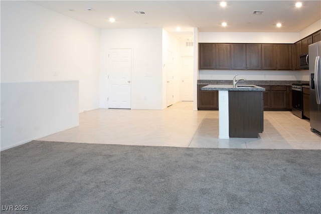 kitchen featuring light tile patterned floors, sink, dark brown cabinets, stainless steel appliances, and a center island with sink