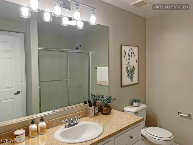 bathroom with a shower with shower door, toilet, and vanity