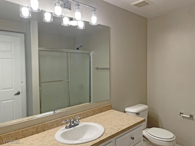 bathroom with vanity, a shower with shower door, and toilet