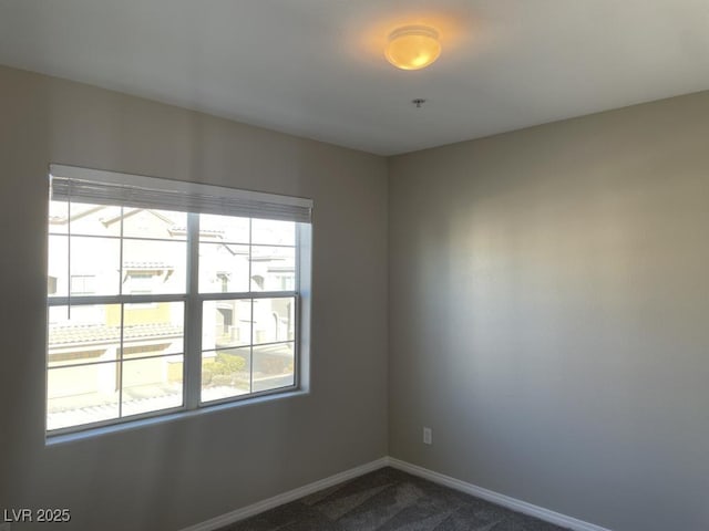 spare room with dark colored carpet and a wealth of natural light