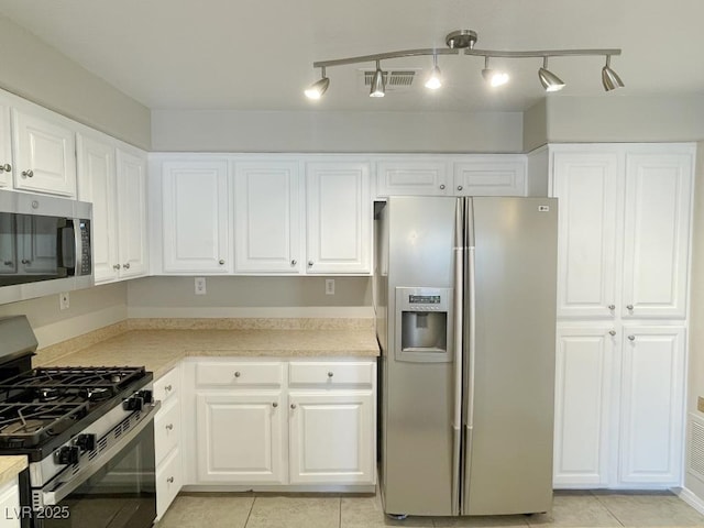 kitchen featuring white cabinets, stainless steel appliances, and light tile patterned floors