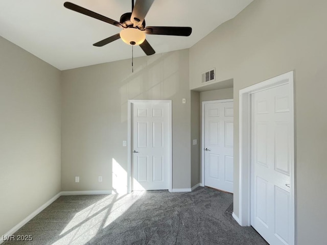 unfurnished bedroom with ceiling fan, dark colored carpet, and lofted ceiling