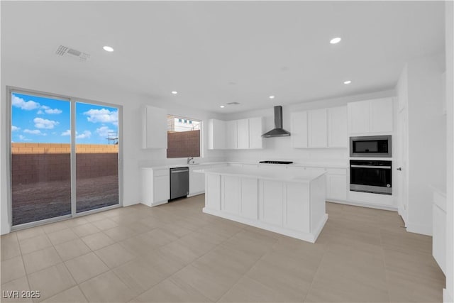 kitchen with a center island, white cabinetry, wall chimney range hood, wall oven, and built in microwave