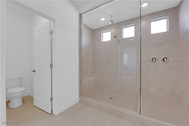 bathroom featuring tiled shower and toilet