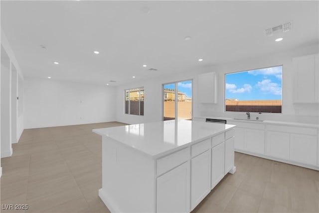 kitchen featuring sink, white cabinetry, light tile patterned floors, and a center island