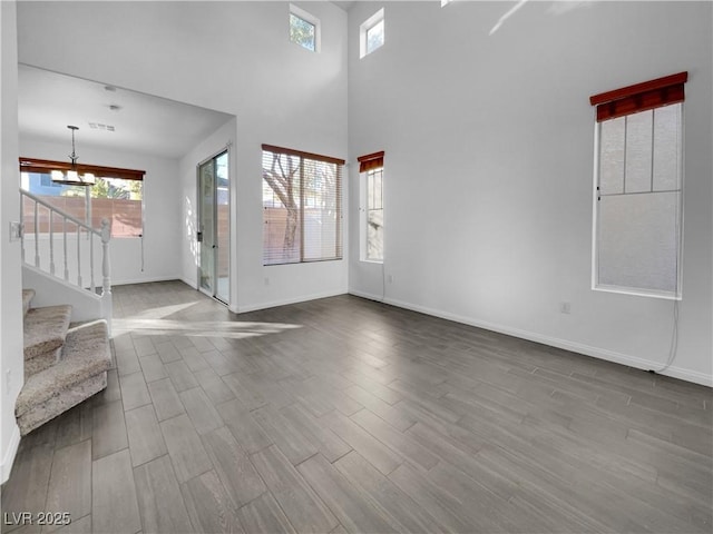 unfurnished living room featuring an inviting chandelier and a towering ceiling