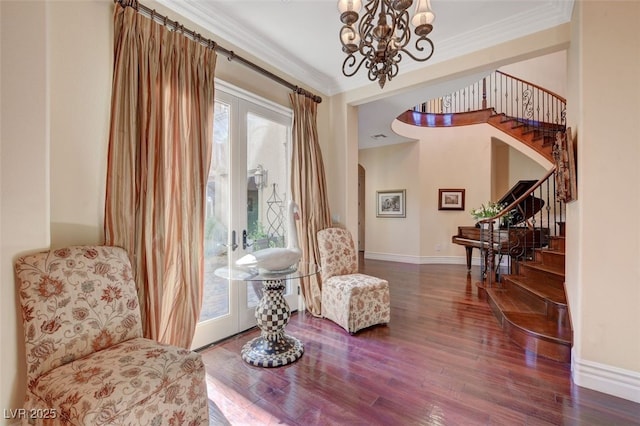 living area with wood-type flooring, ornamental molding, and an inviting chandelier