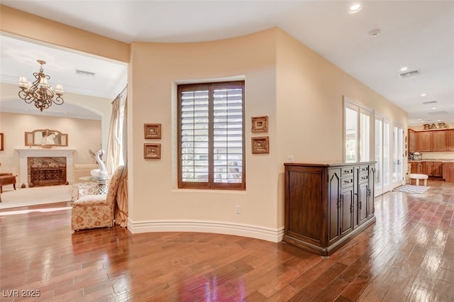 interior space featuring a notable chandelier, wood finished floors, visible vents, and baseboards