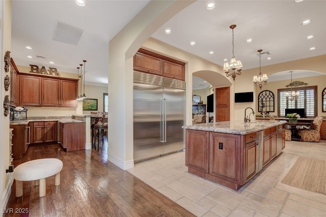 4450 Palisades Canyon Cir, Las Vegas, NV 89129 - kitchen with built in fridge, recessed lighting, a kitchen island with sink, a sink, and light stone countertops