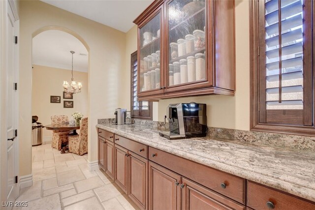 bar featuring stone tile floors, arched walkways, pendant lighting, and baseboards