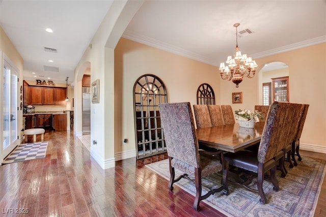 dining room with a notable chandelier, ornamental molding, and dark wood-type flooring